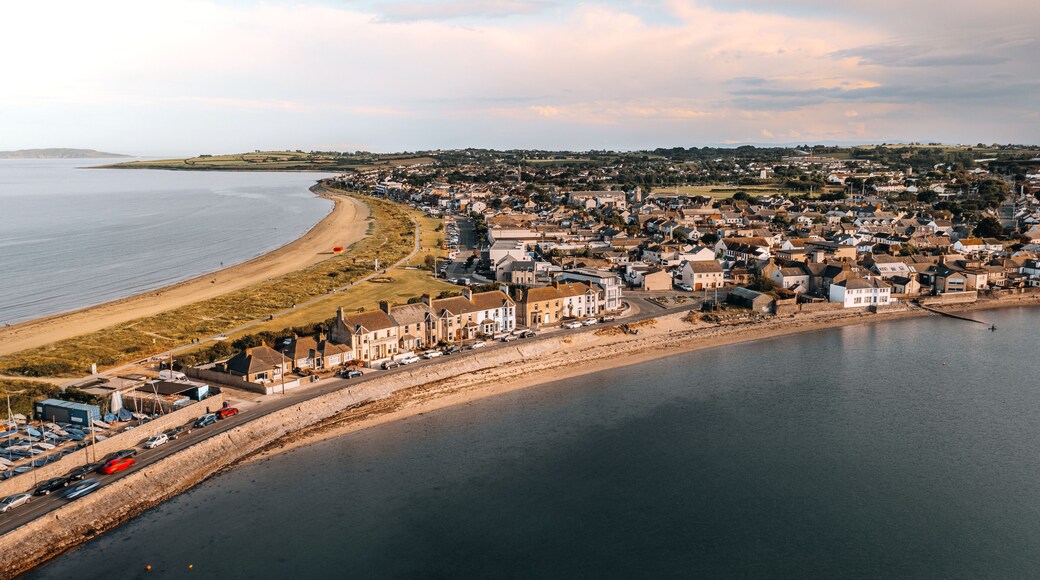 Aerial photograph of the charming beachfront town of Skerries, Ireland, captured around sunset. The image showcases the expansive beach, residential homes, and surrounding countryside.