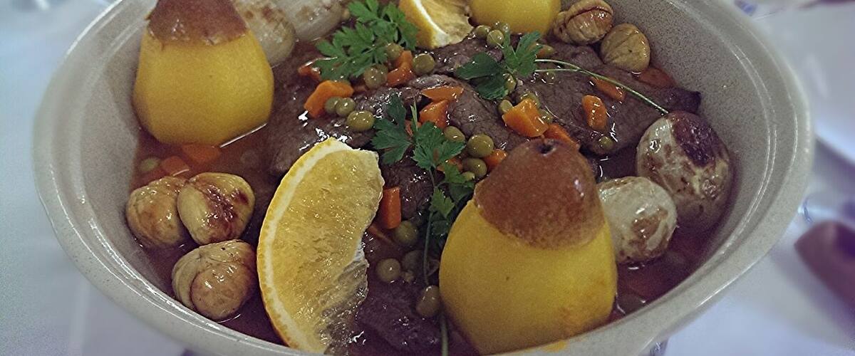 A bowl of stew with potatoes, carrots, and herbs.