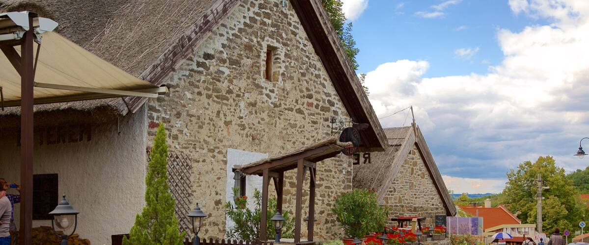 A cobblestone street lined with stone buildings, a wooden fence, and potted plants.