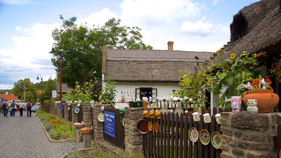 A traditional thatched-roof house with a sign for a pottery shop.