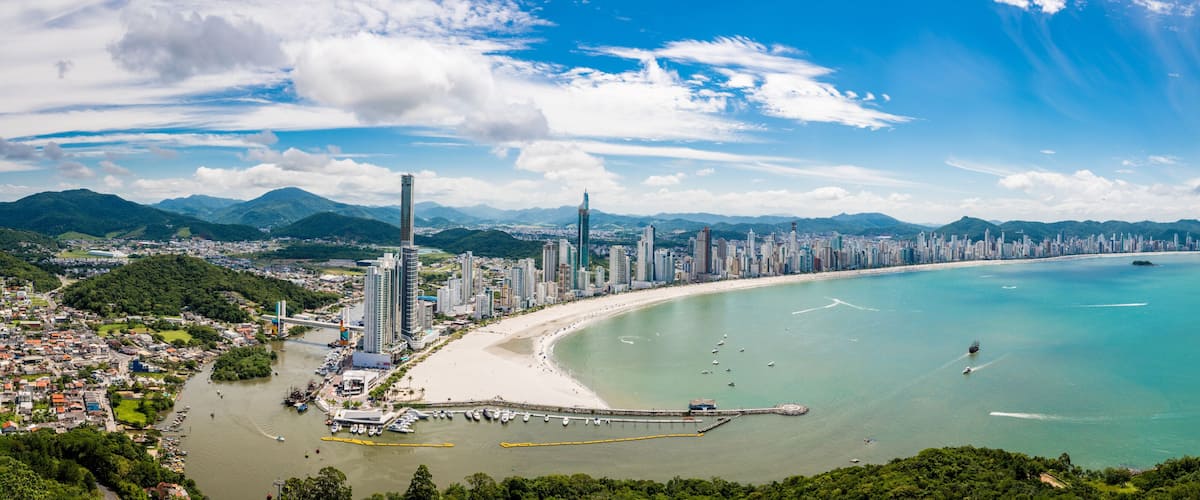 A coastal cityscape with a prominent skyscraper, a beach, and a bay.