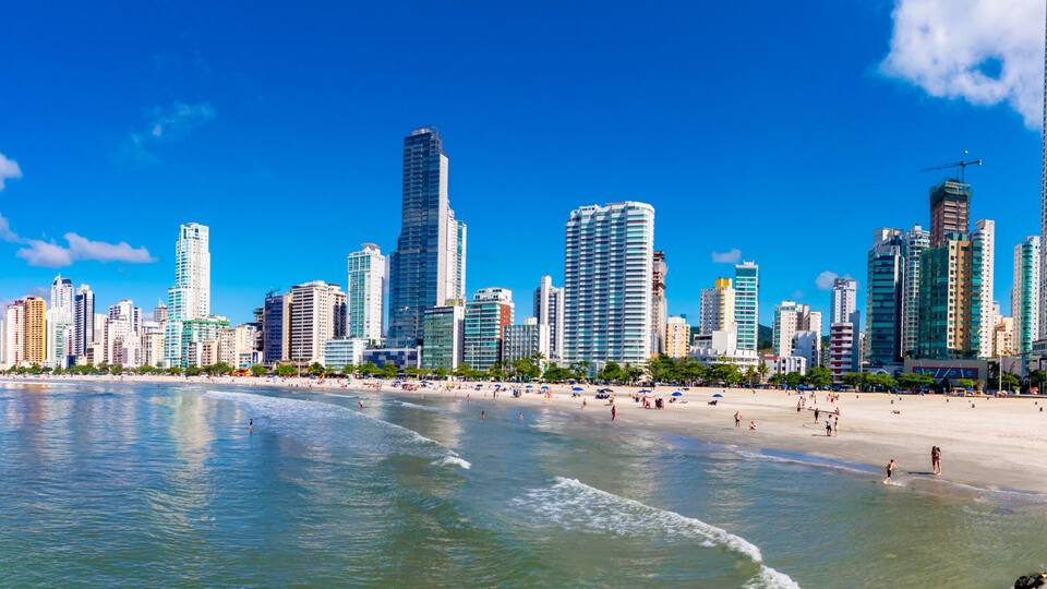 A coastal cityscape with a beach and high-rise buildings.