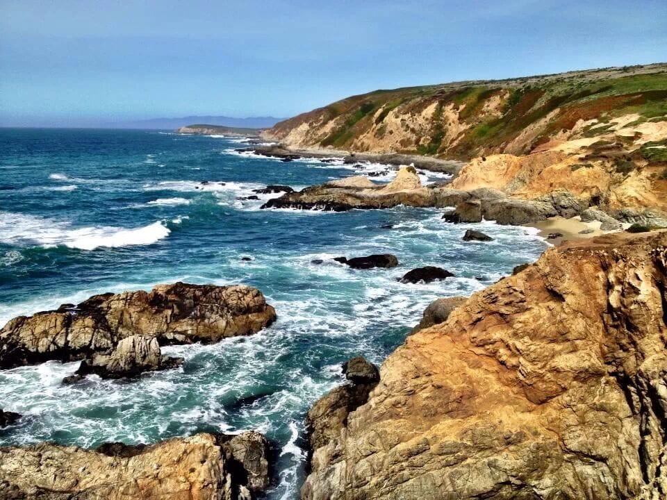 A rugged coastline with rocky outcrops and waves crashing against the shore.