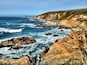 A rugged coastline with rocky outcrops and waves crashing against the shore.