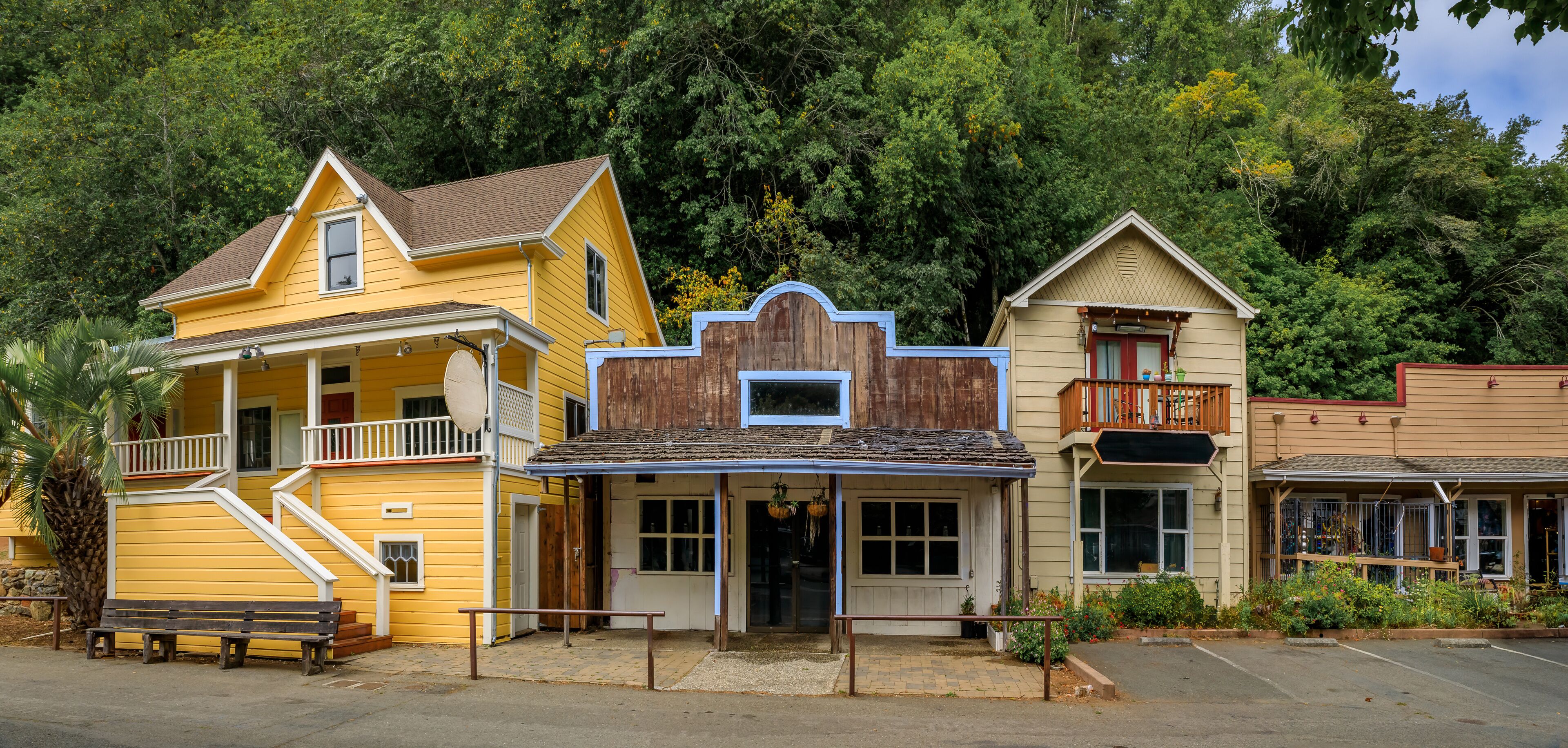Facades of wild western style buildings on a street in Occidental, rural Northern California with a green forest in the background