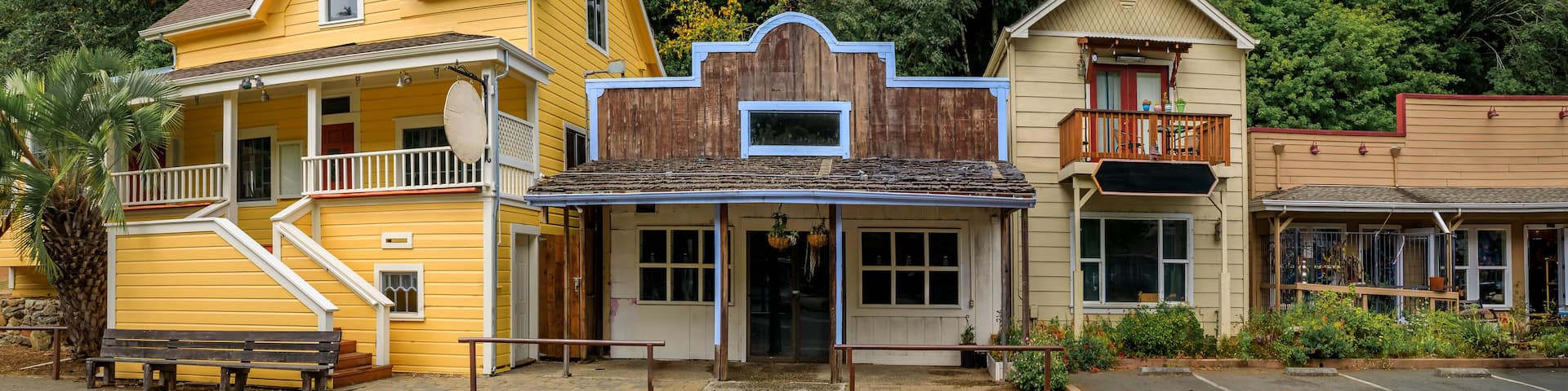 Facades of wild western style buildings on a street in Occidental, rural Northern California with a green forest in the background