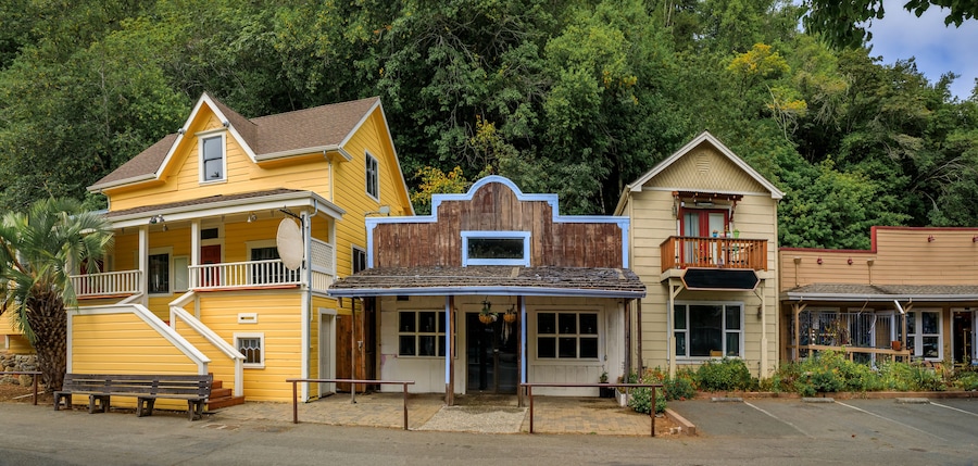 Facades of wild western style buildings on a street in Occidental, rural Northern California with a green forest in the background