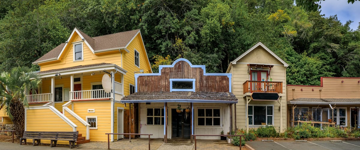 Facades of wild western style buildings on a street in Occidental, rural Northern California with a green forest in the background