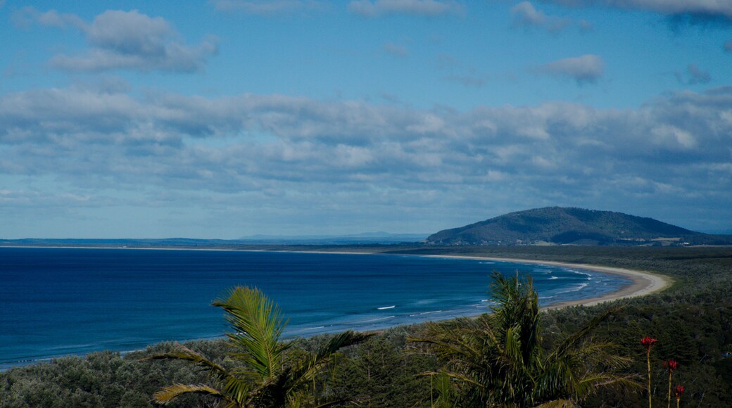 Eine Küstenlandschaft mit Strand, Meer und einer Hügelkette in der Ferne.