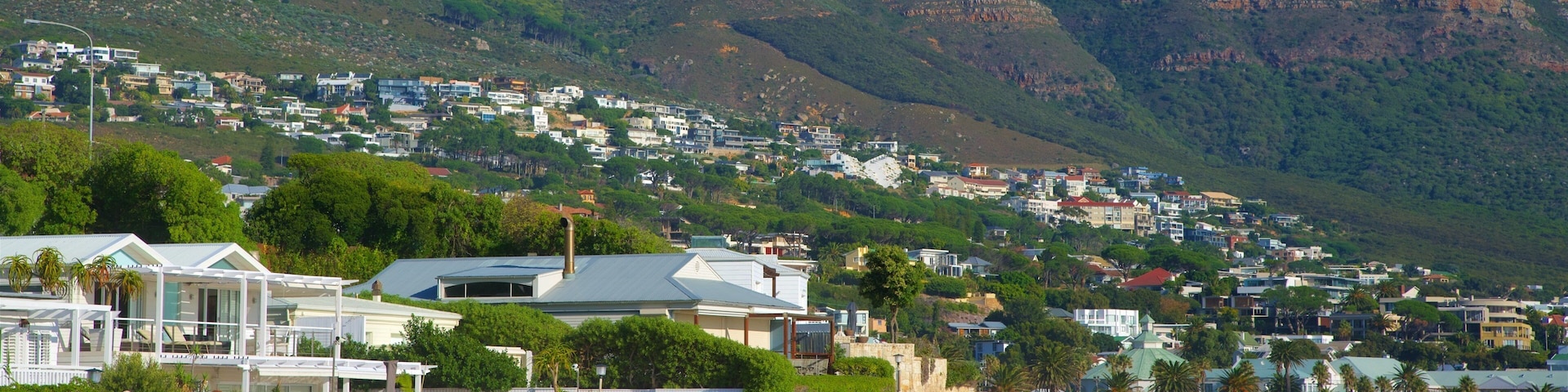 Camps Bay which includes a coastal town, a sandy beach and rocky coastline