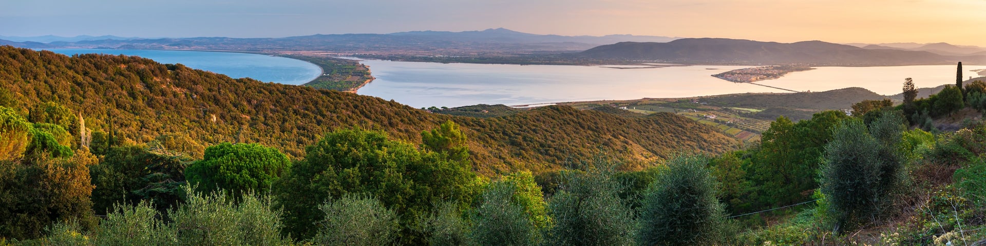 A coastal landscape with a bay, hills, and a clear sky.