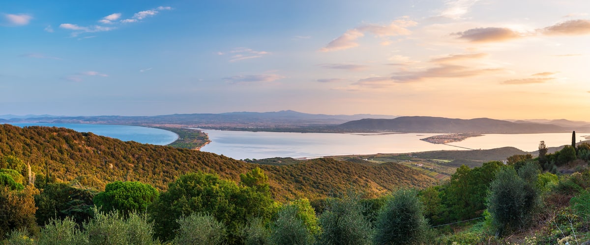 A coastal landscape with a bay, hills, and a clear sky.