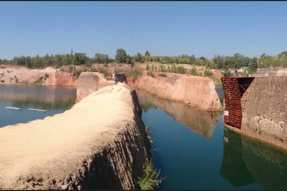 Uma grande barragem com um reservatório de água, paredões rochosos íngremes e vegetação escassa.
