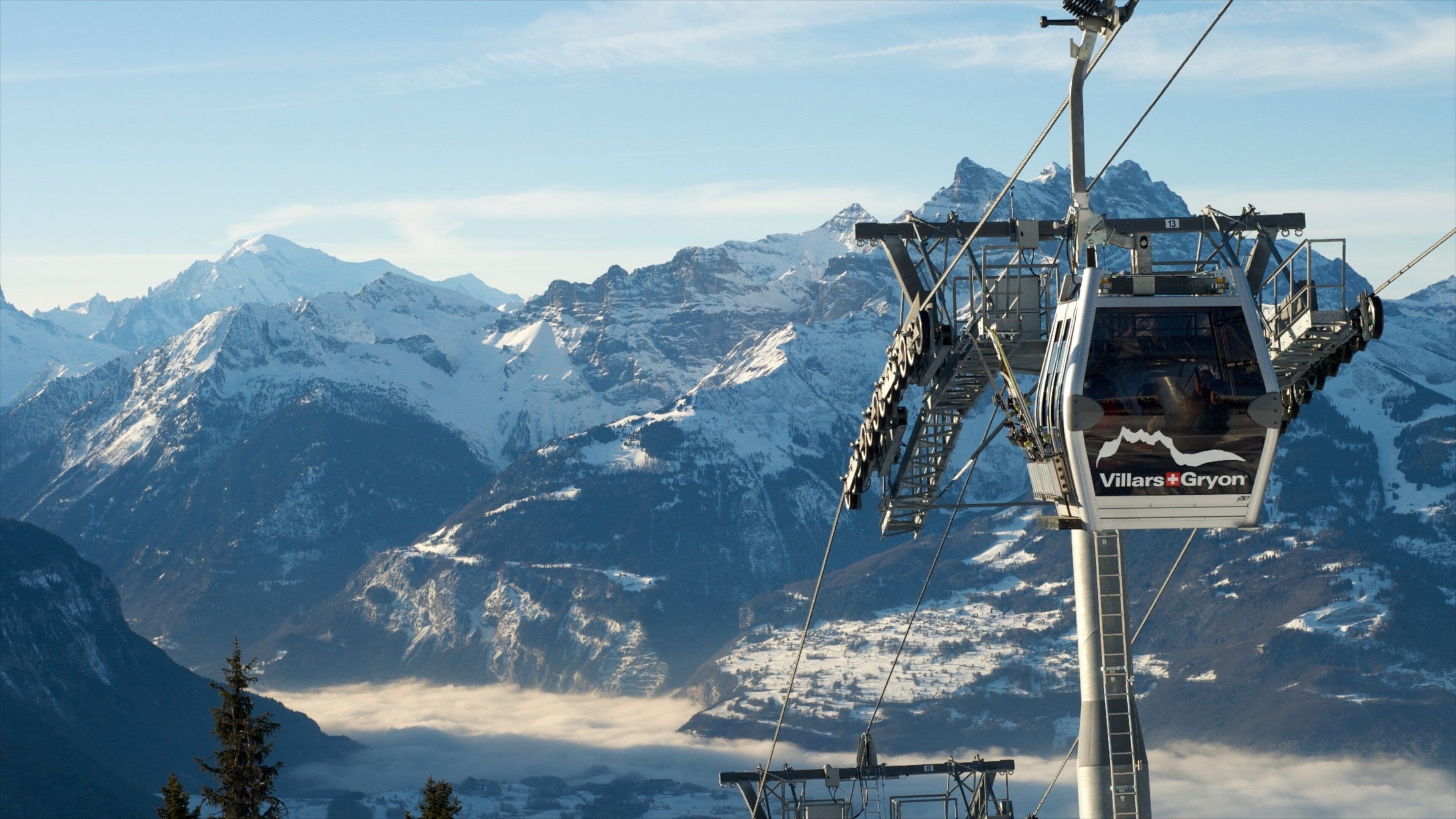 A chairlift with the text "Villers-Gryon" against a backdrop of snow-covered mountains and a clear sky.
