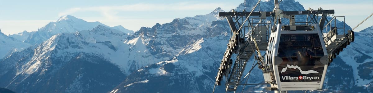 A chairlift with the text "Villers-Gryon" against a backdrop of snow-covered mountains and a clear sky.