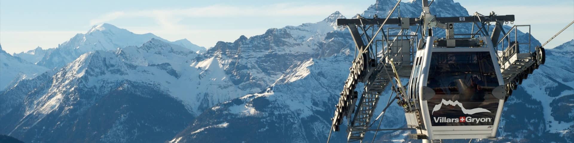 A chairlift with the text "Villers-Gryon" against a backdrop of snow-covered mountains and a clear sky.