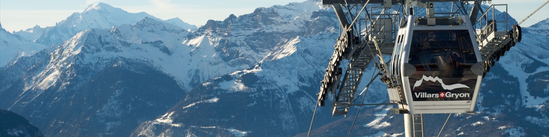 A chairlift with the text "Villers-Gryon" against a backdrop of snow-covered mountains and a clear sky.