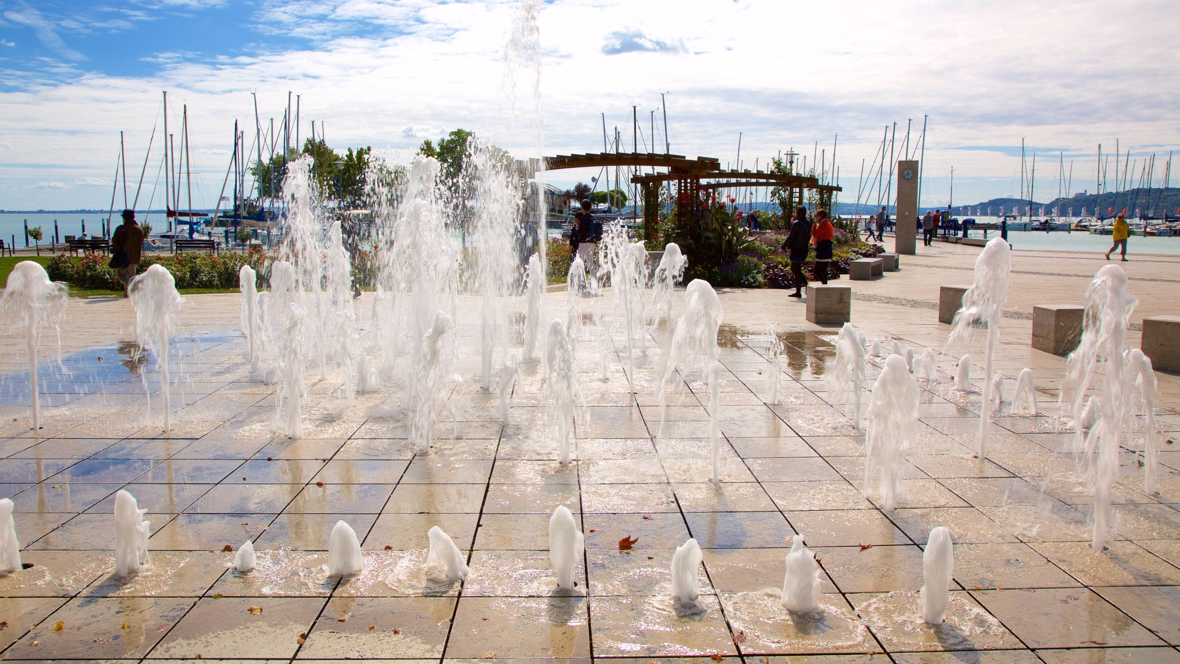 A public square with a water fountain display and a clock tower.