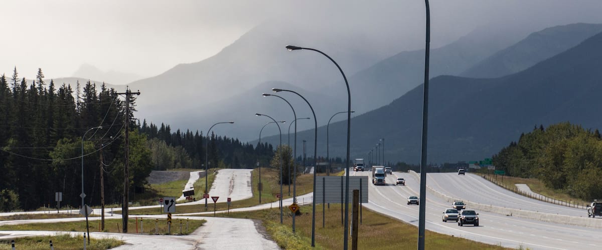 A highway with multiple lanes, streetlights, and a mountain in the background.