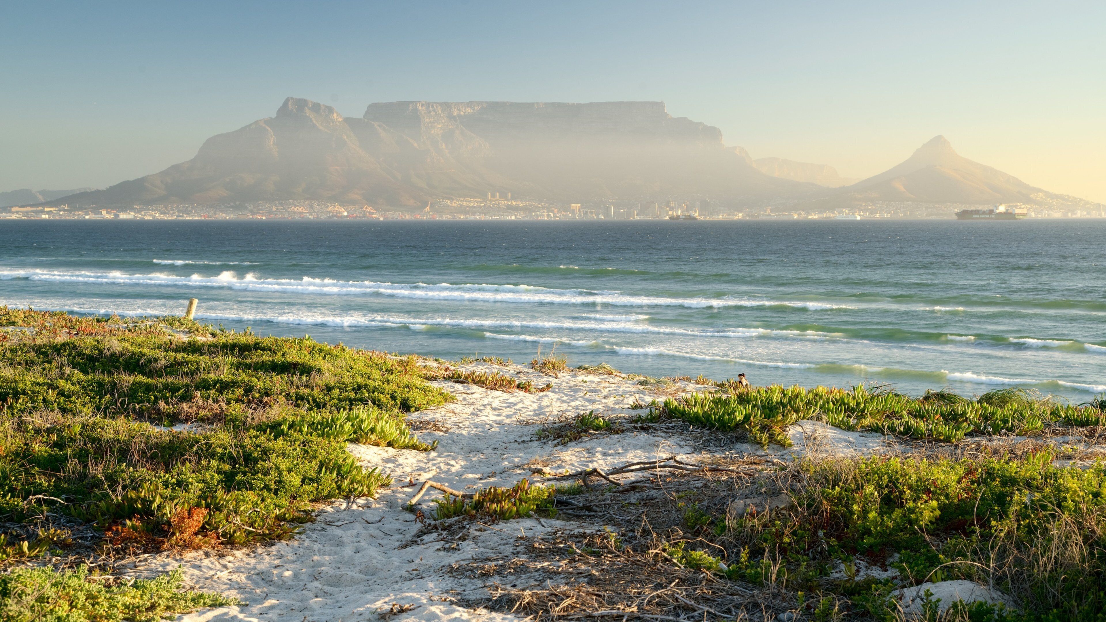 Tableview inclusief een zandstrand, golven en bergen