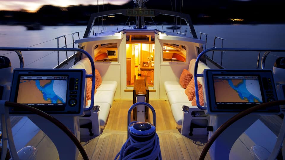 A boat's deck with two screens displaying maps, a central seating area, and a control panel.