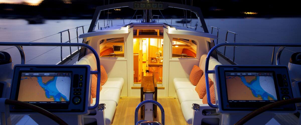 A boat's deck with two screens displaying maps, a central seating area, and a control panel.