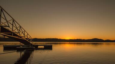 Beautiful yellow orange sunrise sunset over Dale Hollow Lake with a bridge to a fishing pier. Concepts of vacation, travel, tourism