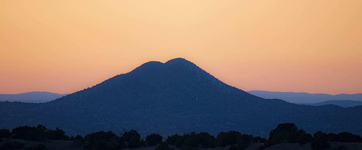 A mountain silhouette against a sunset sky.
