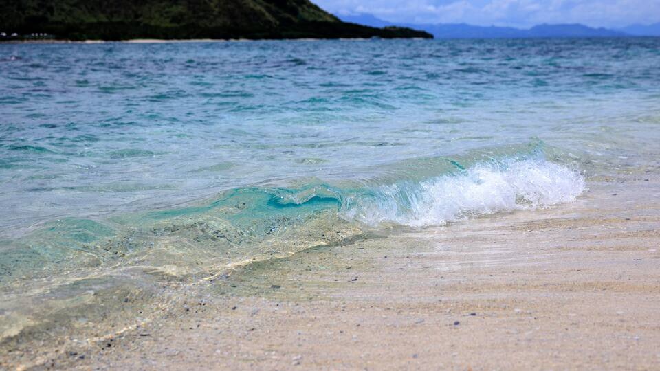 A beach with clear turquoise water and a sandy shore.