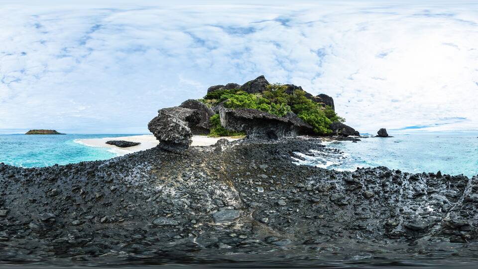 A rocky island with a small beach and turquoise waters.