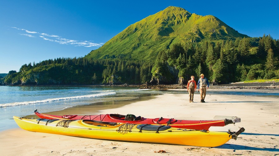 Kodiak Island featuring a sandy beach, mountains and kayaking or canoeing