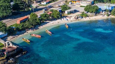 Un pueblo costero con aguas azul cristalino, barcos y edificios.