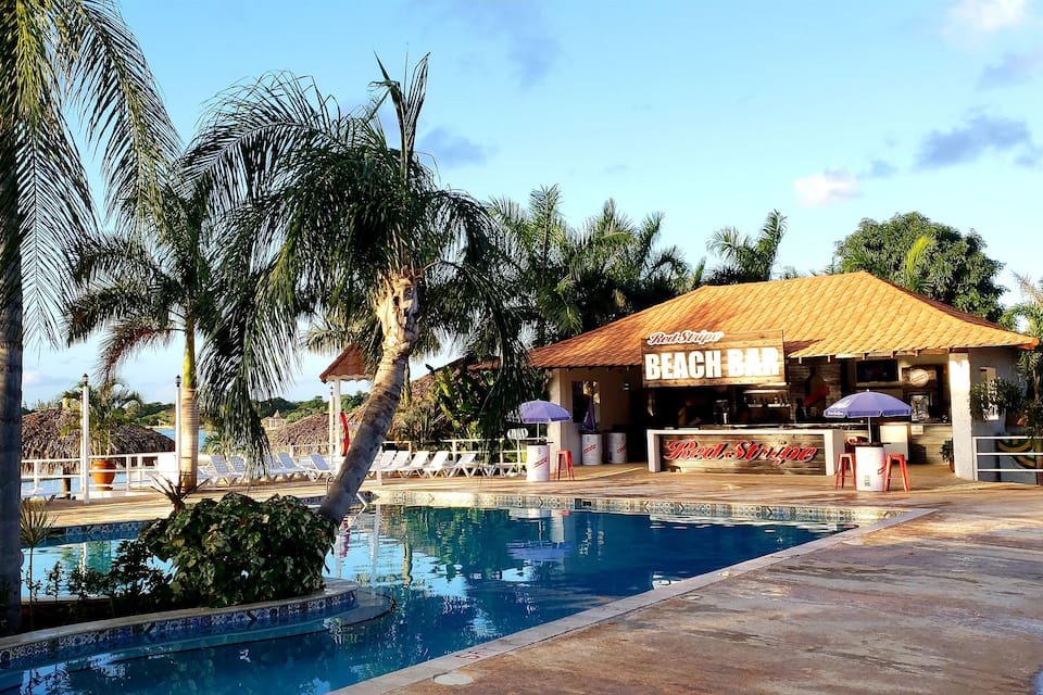 A poolside area with a beach bar named 'Red Stripe'.
