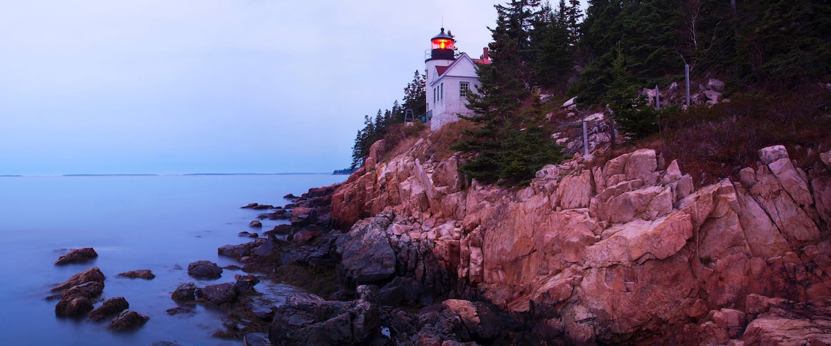A lighthouse on a rocky cliff by the sea.