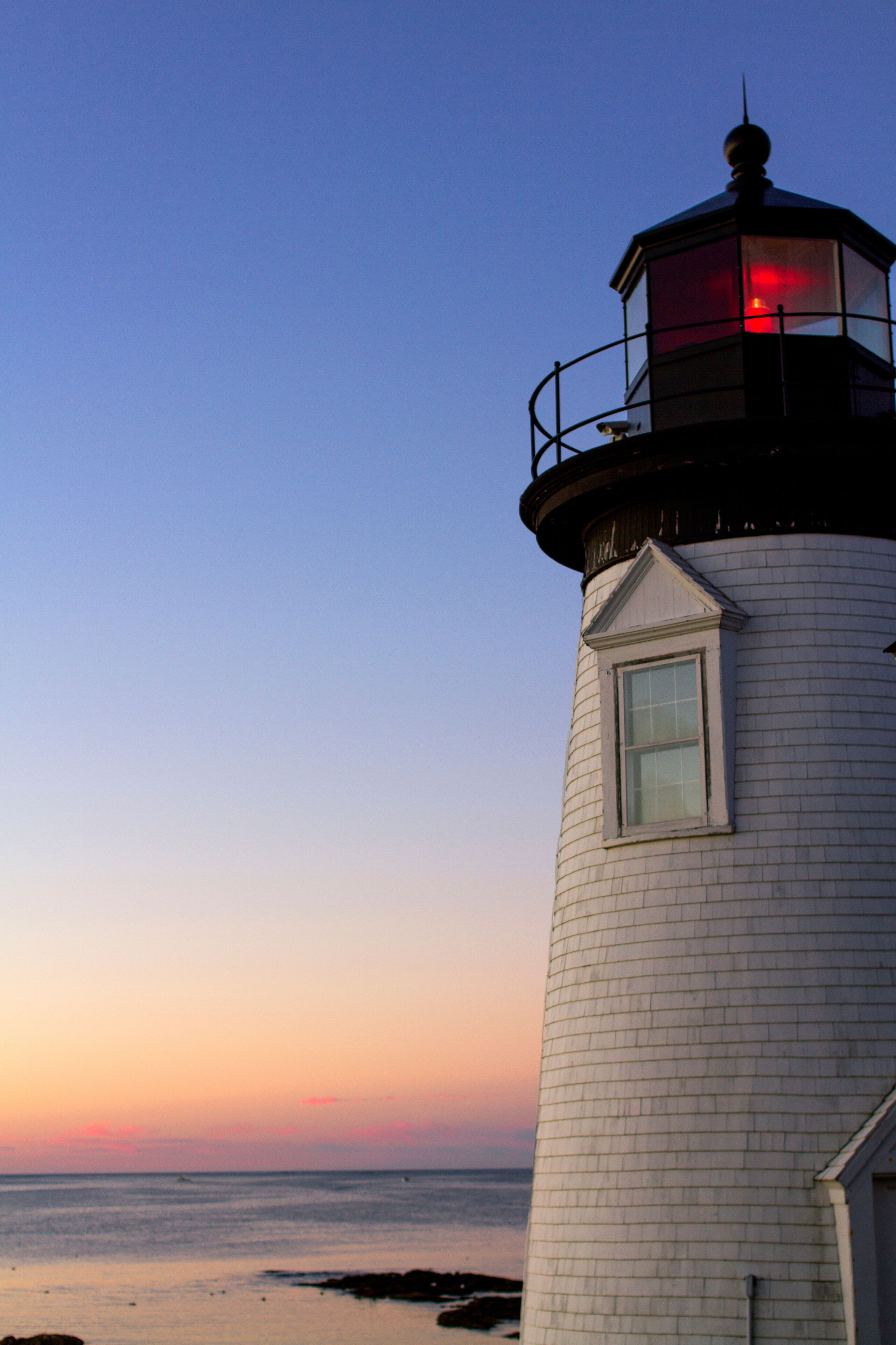 Low angle view of Prospect Harbor Point Light against sea and dramatic sky during sunset