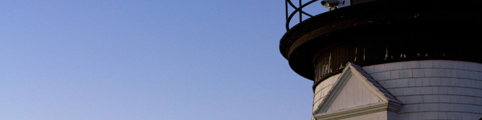 Low angle view of Prospect Harbor Point Light against sea and dramatic sky during sunset