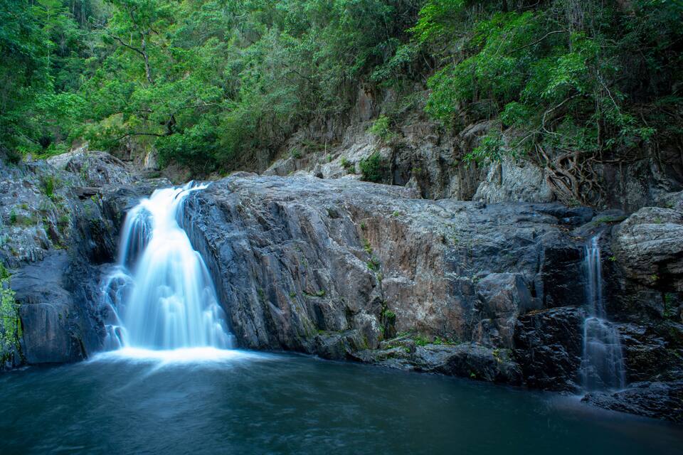 A waterfall cascading over a rocky cliff surrounded by dense green foliage.