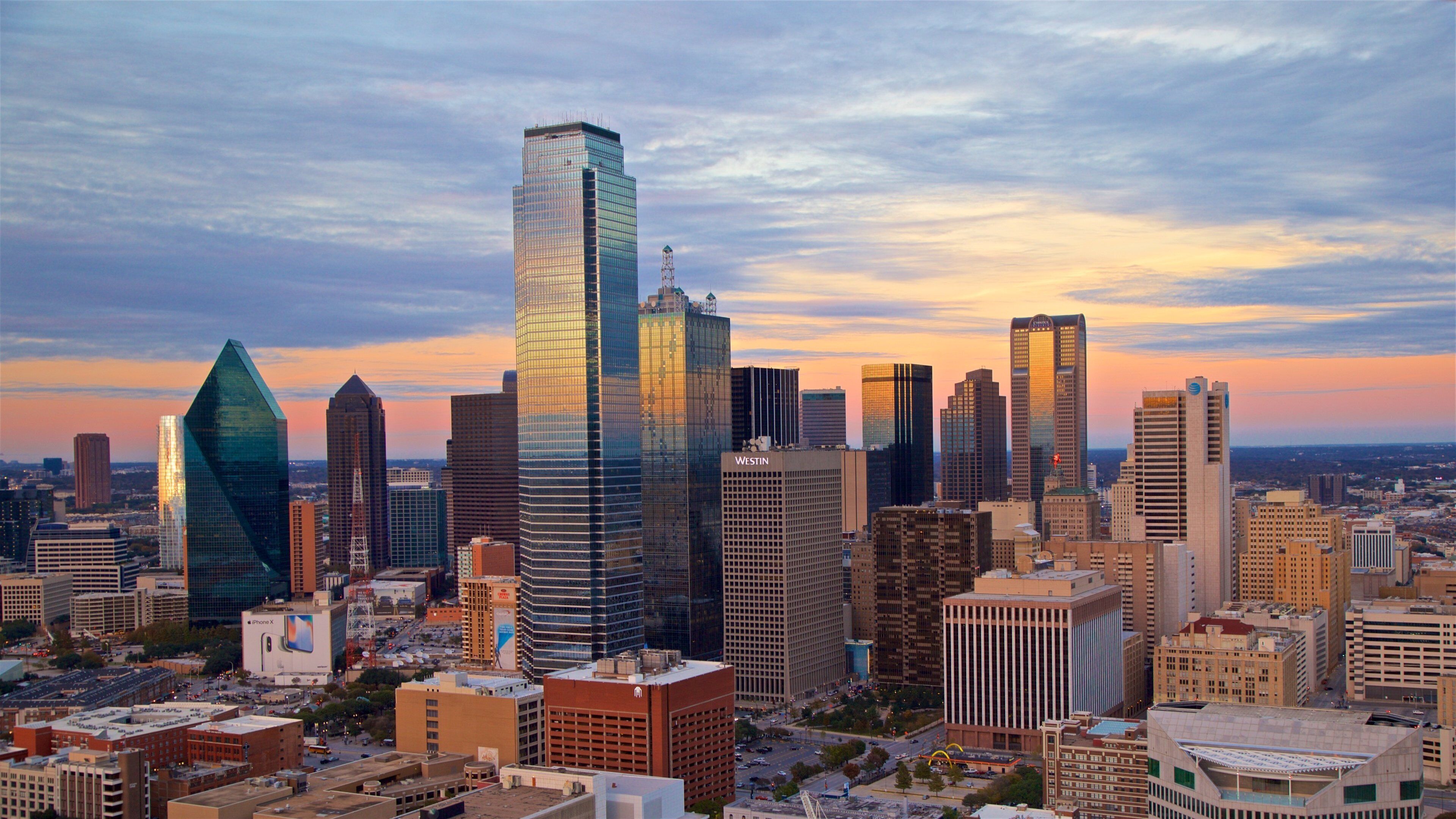 A cityscape with modern skyscrapers and a sunset sky.