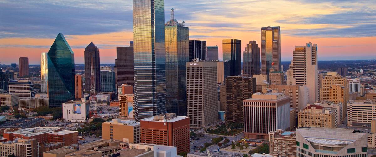A cityscape with modern skyscrapers and a sunset sky.