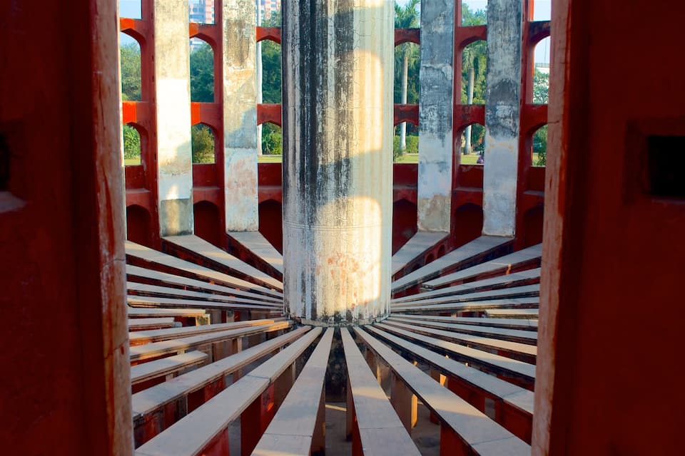Vista a través de una estructura roja y blanca con una columna central y bancos.
