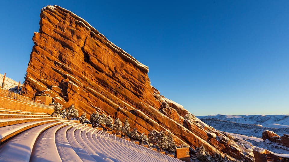 A snow-covered amphitheater with a large rock formation in the background.