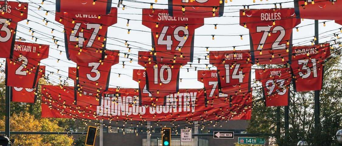 A street with red sports jerseys hanging overhead, displaying numbers and names.