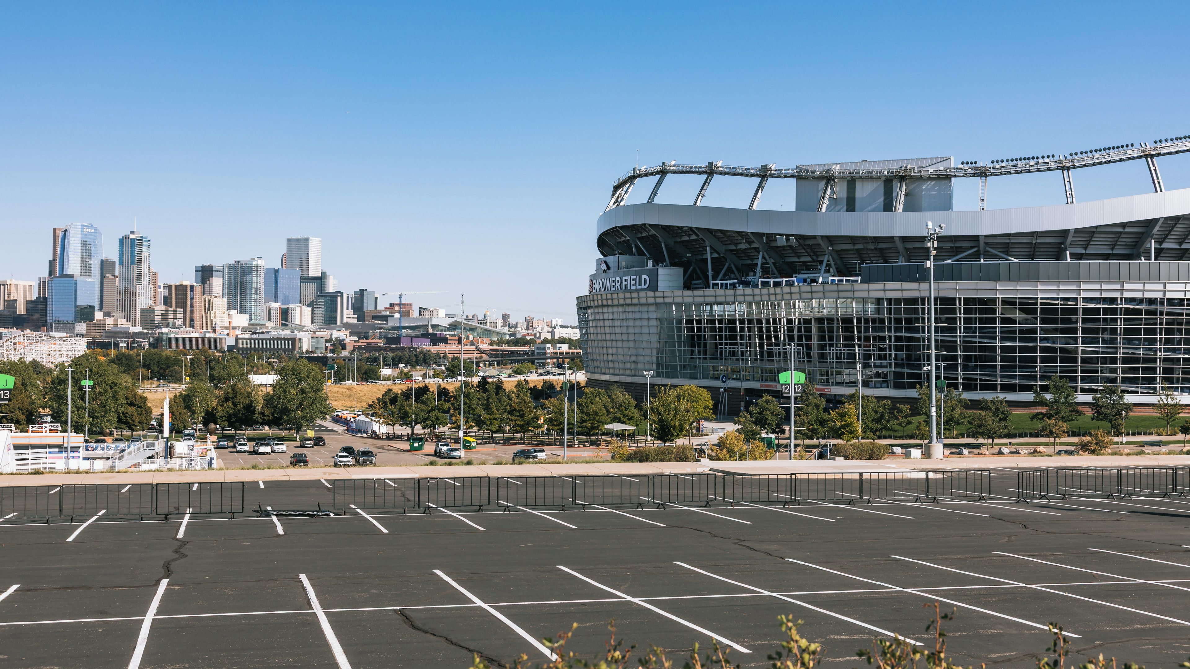 A parking lot in front of a stadium with a city skyline in the background.