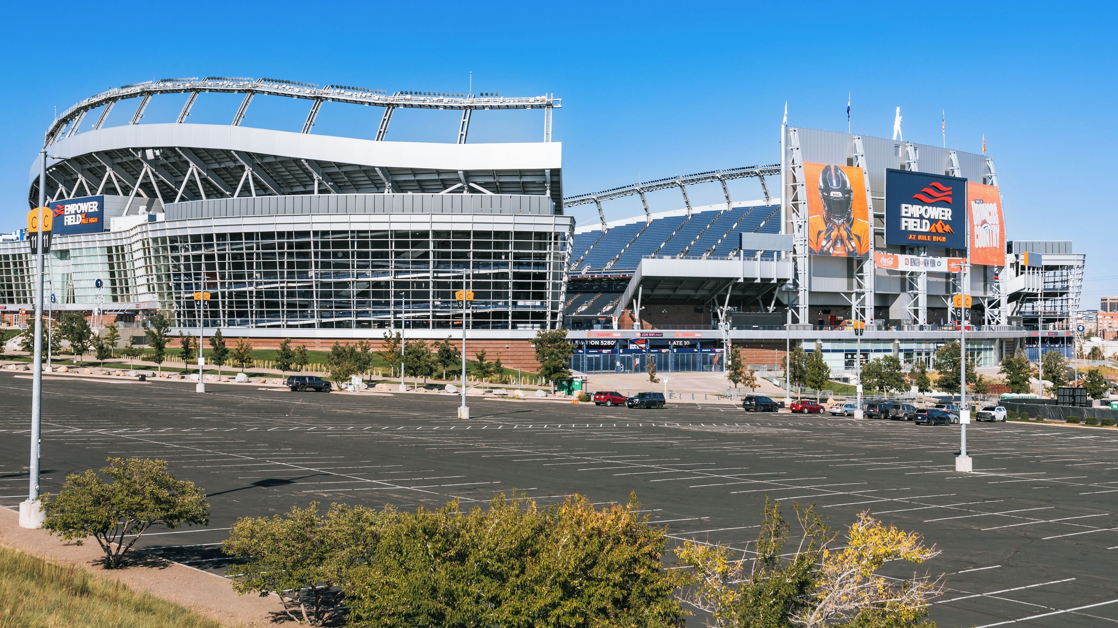 A large sports stadium with a modern design, featuring a prominent glass facade and a large digital scoreboard.