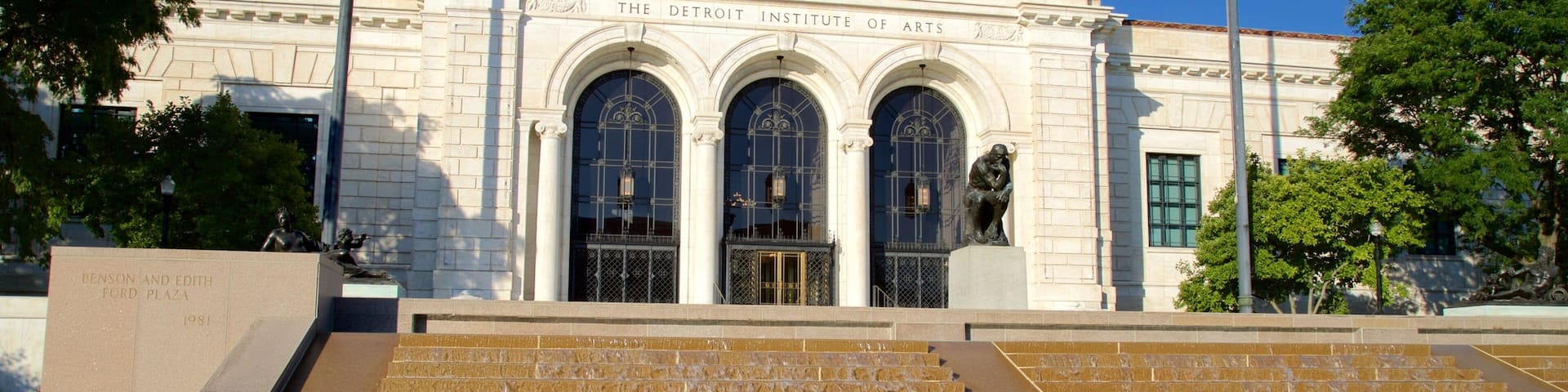 The Detroit Institute of Arts building with classical architecture, steps leading up to the entrance, and a statue in front.