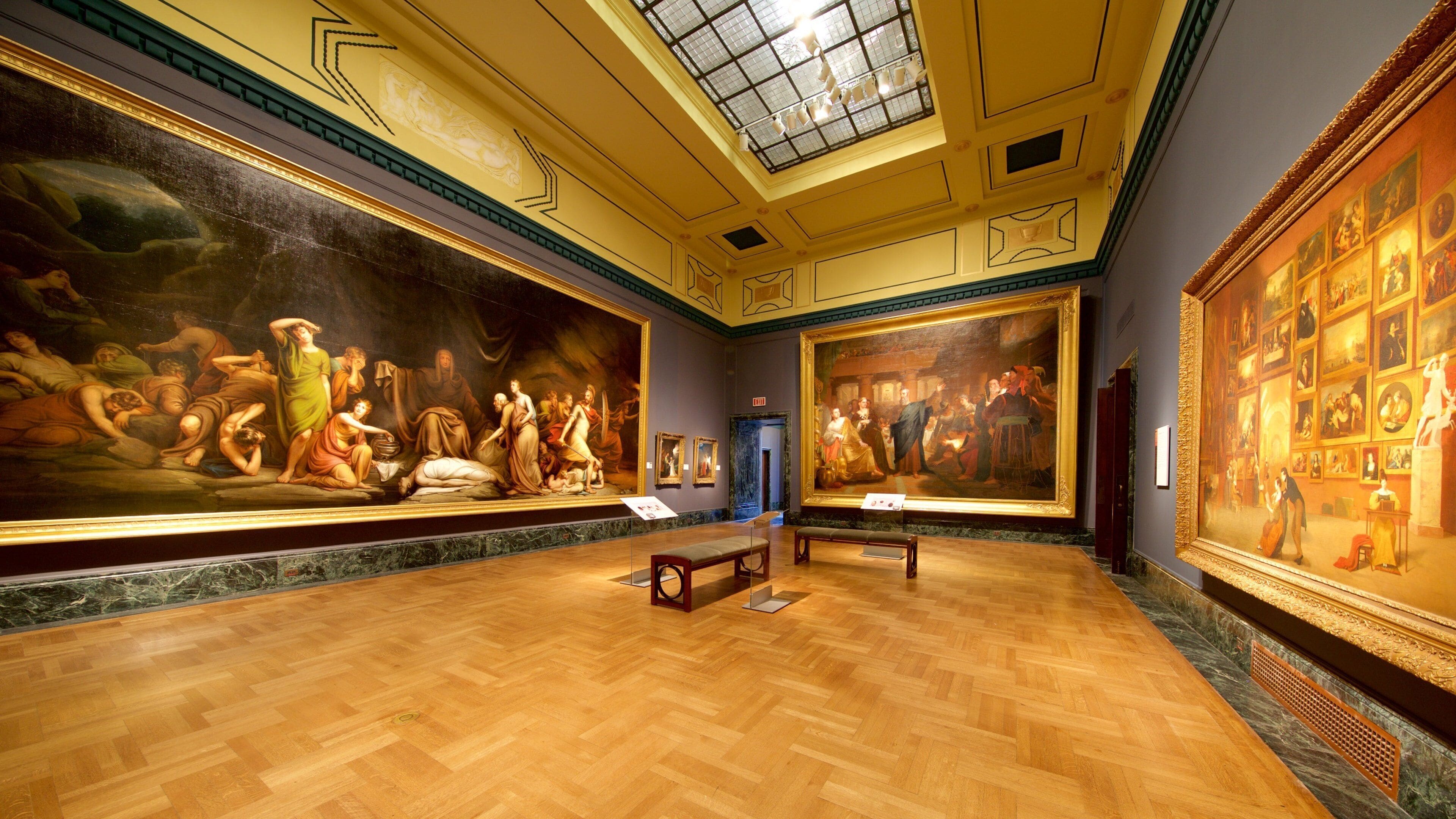 Ein Museuminneres mit großen Gemälden aus der Klassik, Holzböden und einem Oberlicht.