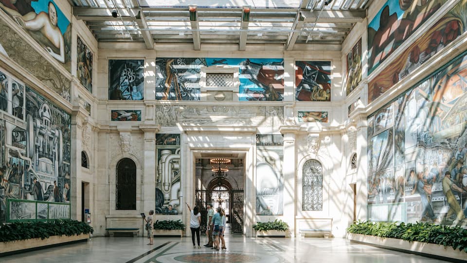 Ein beeindruckender Atrium mit hohen Decken, aufwendigen Wandgemälden und klassischer Architektur.