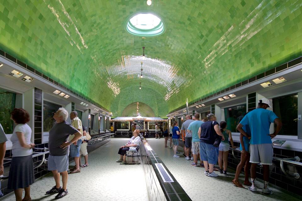 Une gare avec un plafond recouvert de carreaux verts et un espace d’attente central.