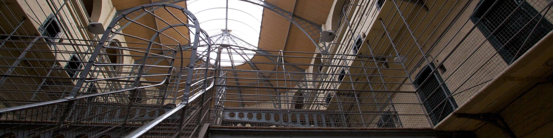 A complex metal structure with multiple staircases and railings inside a building with arched ceilings and windows.