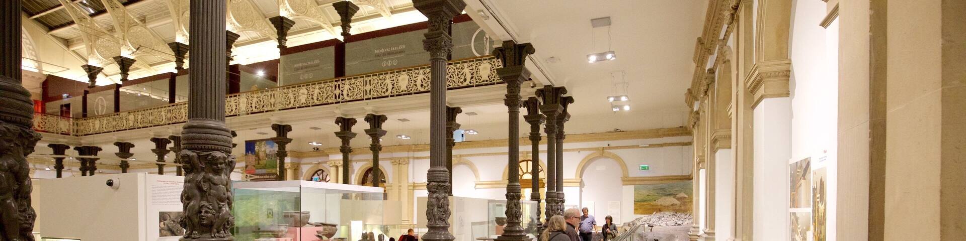 An indoor museum with classical architecture, including ornate columns and a glass railing.